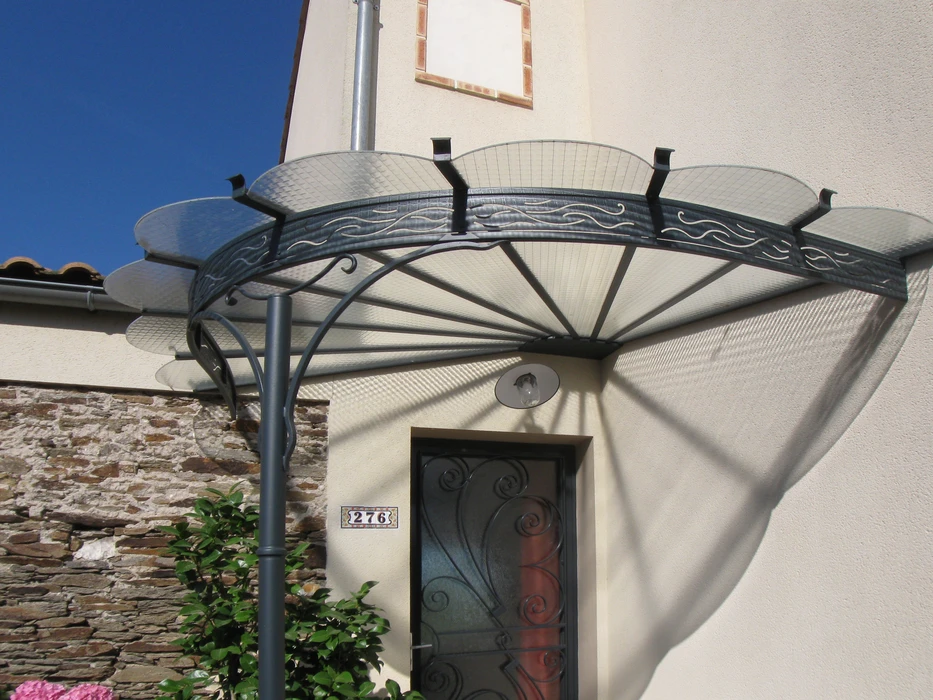 Façade d'immeuble ancien avec marquise en fer forgé ornementée de volutes et arabesques, structure métallique bordeaux supportant une toiture translucide