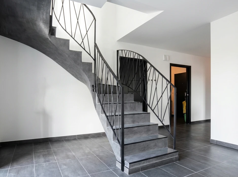 Escalier intérieur en béton ciré gris anthracite, structure autoportante avec mur courbe