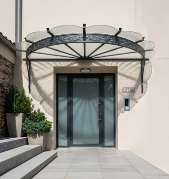 Façade d'immeuble ancien avec marquise en fer forgé ornementée de volutes et arabesques, structure métallique bordeaux supportant une toiture translucide
