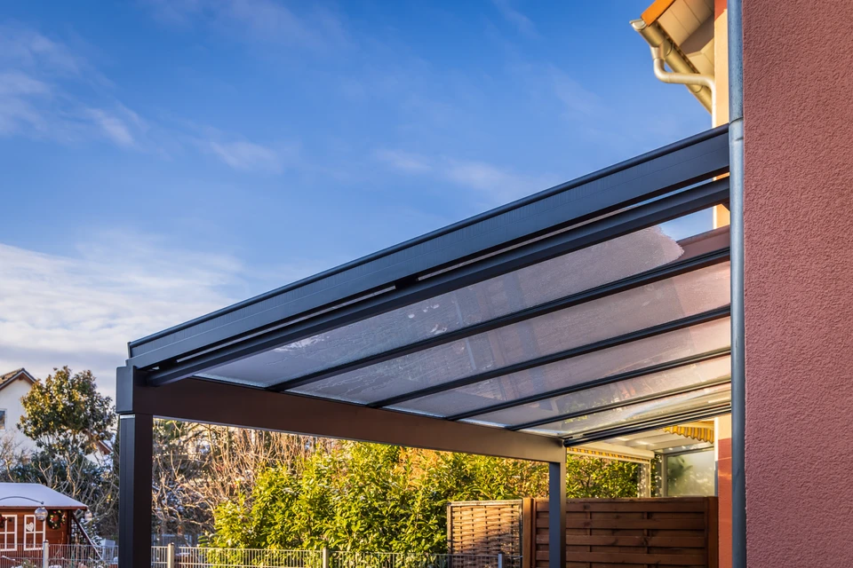 Terrasse extérieure aménagée avec pergola moderne en bois et acier, équipée d'un espace barbecue intégré et coin salon avec cheminée