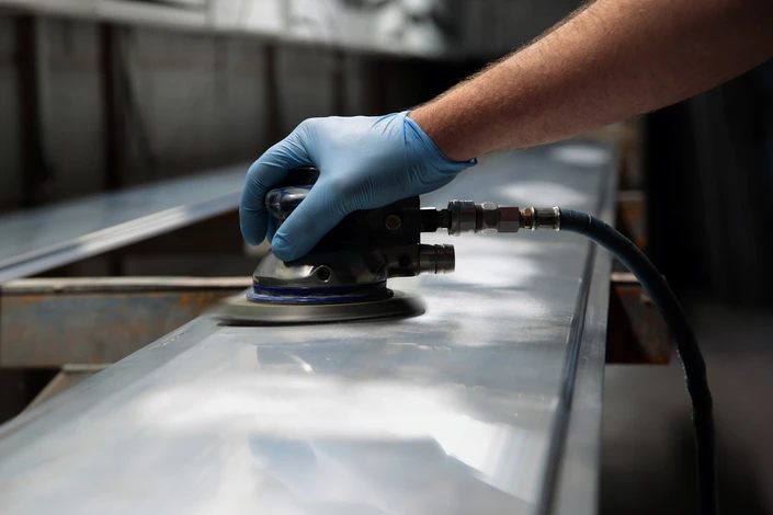 Artisan travaillant sur une pièce métallique avec projection d'eau et de particules
