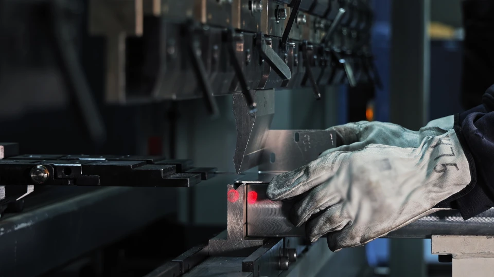 Artisan soudeur en action dans un atelier intérieur, portant masque de protection et gants de sécurité, travaillant sur des structures métalliques avec arc électrique visible